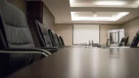 Empty conference room with black chairs, projector, and glasses on table. Ideal for business meetings.