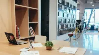 A modern office workspace featuring a laptop, documents, and a potted plant on a wooden table.