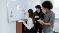 Young professionals brainstorming and designing a product prototype on a whiteboard.