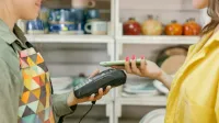 Un cliente realiza un pago sin efectivo usando un teléfono inteligente en una tienda minorista. La tecnología moderna cumple con la comodidad.