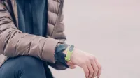A person wearing a green fitness tracker and winter clothing outdoors. Perfect for health and lifestyle themes.