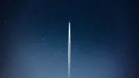 A rocket streaks through a starry night, leaving a trail in outer space.