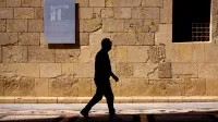 Silhouette of a man walking by Museo de la Catedral wall in Murcia, Spain.