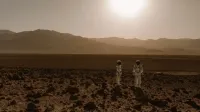 Astronauts in space suits explore a rocky, desert-like terrain resembling Mars at sunset.