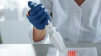 Close-up of a scientist using a pipette in a lab with a focus on sterile procedures.