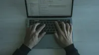Vista cercana de un programador que codifica en una computadora portátil, mostrando el desarrollo de software moderno.
