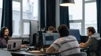 Team of developers working together on computers in a modern tech office.