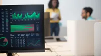 Modern office with financial trading screens and a diverse team discussing strategies.