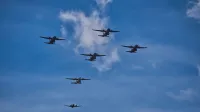 A group of airplanes flying in formation against a vivid blue sky over Mexico City, captured in daylight.