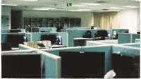 Amplio piso de oficina con filas de cubículos vacíos y monitores de computadora.