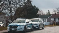 Una calle suburbana con un coche de policía y vehículos estacionados. capturado a la luz del día.