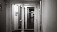 Empty hospital corridor in black and white, emphasizing open doors and healthcare environment.