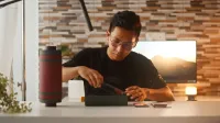 Un joven desempaqueta un smartphone, mostrando la tecnología moderna en un ambiente interior acogedor.