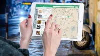 Hands using a digital map on a tablet in an urban setting at night, illustrating navigation and technology.