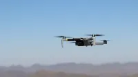 Drone flying over a desert landscape under clear blue skies.