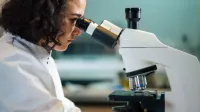 Un científico enfocado examina las muestras bajo un microscopio en un entorno de laboratorio.