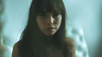 Artistic portrait of a woman with long hair and bangs in a soft, moody setting.