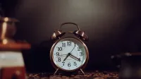 Rustic vintage alarm clock surrounded by coffee beans, providing a warm nostalgic feel.