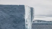A breathtaking view of a massive iceberg in Antarctica surrounded by the deep blue sea.