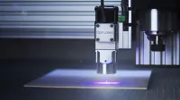 Close-up of a laser engraver working on a surface under blue lighting.