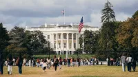 Los turistas se reúnen fuera de la Casa Blanca en un día soleado, capturando la grandeza del hito.
