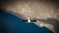 A satellite hovering above Earth's coastline, captured from space.