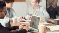 Professionals collaborating in an office setting, focused on digital data analysis during a meeting.