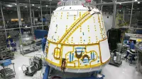 Anonymous male mechanic in uniform fixing detail of spacecraft while working at modern headquarter of industrial factory