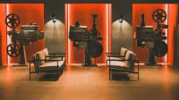 A cozy retro cinema room showcasing vintage film projectors and comfortable seating.