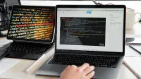 A developer writing code on a laptop, displaying programming scripts in an office environment.