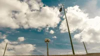 View of a street lamp and fence under a picturesque cloudy blue sky in Madrid, Spain.
