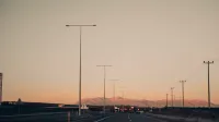 Highway with lampposts at dusk and mountains in the background.