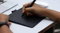 Close-up of hands using a graphic tablet with stylus for creative design, shot in Chennai, India.