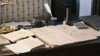 Acogedor estudio con escritorio vintage, libros abiertos y pluma para una sensación literaria clásica.