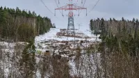 High-voltage power lines stretch through a wintry forest landscape, emphasizing energy and nature.