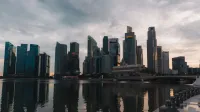 Dramatic skyline of Singapore reflecting on waterfront at dusk with towering skyscrapers.