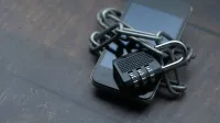 Close-up of a smartphone wrapped in a chain with a padlock, symbolizing strong security.