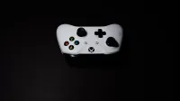 A close-up of a white Xbox controller on a black background, highlighting its modern design.