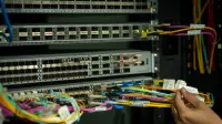 A hand managing fiber optic cables in a server room, showcasing modern connectivity.