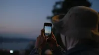 Persona tomando una foto del puente del Bósforo en Estambul al anochecer usando un smartphone.