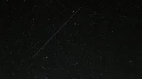 Captivating starry night sky with a visible shooting star streaking across the cosmic backdrop.