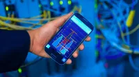 Hand holding smartphone displaying network analysis in high-tech server environment.