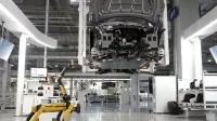 Un perro robótico supervisa un ensamblaje de automóviles automatizado en un entorno de alta tecnología de fábrica.