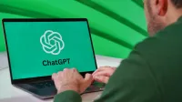 Person typing on a laptop displaying ChatGPT logo with a green vibrant setting.