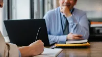 Crop anonymous female filling questionnaire when applying for job sitting in employer office