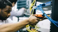 Side view crop concentrated African American engineer repairing equipment by using electric screwdriver