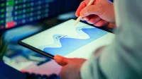 Professional analyzing data chart on a tablet with stylus in an office setting.