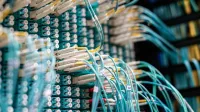 From below of long thin blue cables connected to row of small white connectors on system block in data center