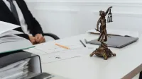 A legal professional's workspace featuring Lady Justice statue, documents, and a laptop.