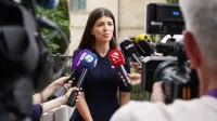 Un portavoz se involucra con los medios durante una entrevista de prensa al aire libre rodeada de micrófonos.